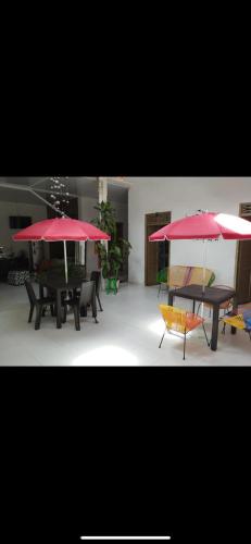 two tables and chairs with red umbrellas in a room at Hotel San Martin Plaza in Villeta