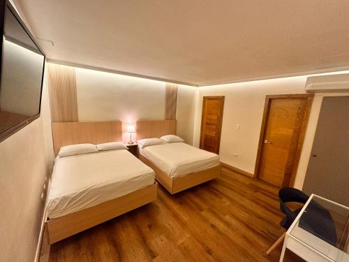 um quarto de hotel com duas camas e uma televisão de ecrã plano em Hotel La Colonia em Santo Domingo