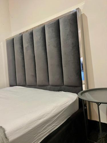 a bed with a padded headboard with a table at Borehamwood stay in Borehamwood