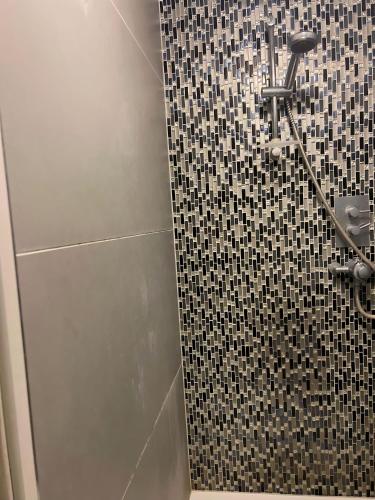 a bathroom with a shower with a black and white tiles at Borehamwood stay in Borehamwood