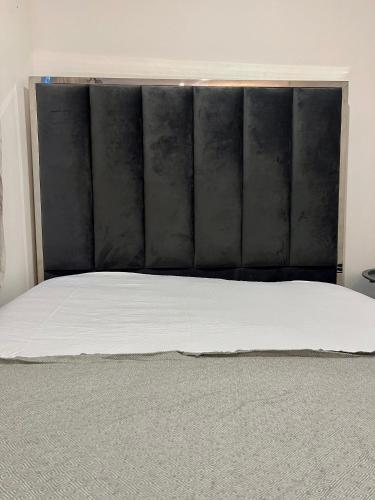 uma cama com uma cabeceira preta num quarto em Borehamwood stay em Borehamwood
