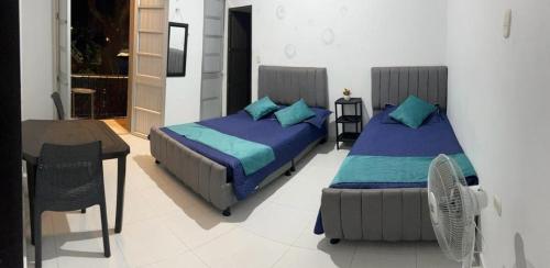 a bedroom with two beds and a table and a chair at Hotel San Martin Plaza in Villeta
