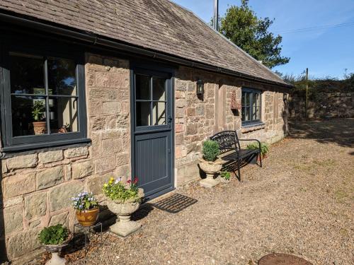 a stone building with a door and some plants at Stable Lodge in Berwick-Upon-Tweed