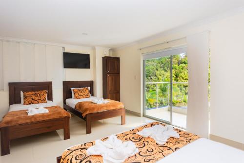 a bedroom with two beds and a window at Hotel Verony Guatape in Guatapé