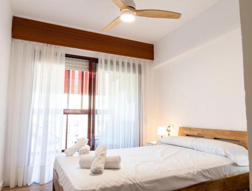 Schlafzimmer mit einem Bett mit weißer Bettwäsche und einem Fenster in der Unterkunft Benidorm beach, playa de Benidorm in Benidorm