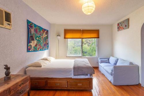 a bedroom with a bed and a couch and a window at Espacioso y Cómodo Dpto. Bien Iluminado en Mty in Monterrey