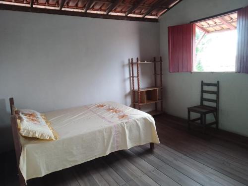 um quarto com uma cama, uma cadeira e uma janela em Casa à 200 metros da praia em Porto Seguro