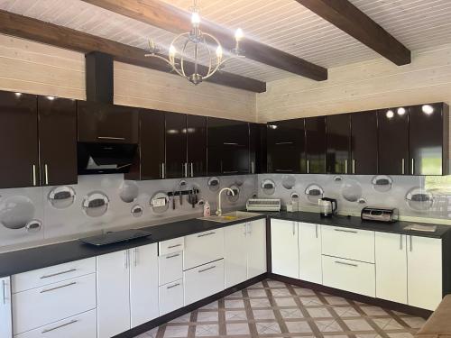 a large kitchen with white cabinets and a chandelier at Кольорове життя in Mykulychyn
