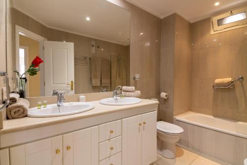uma casa de banho com 2 lavatórios, um WC e um espelho. em Terrazas del Duque II Hideaway em Adeje