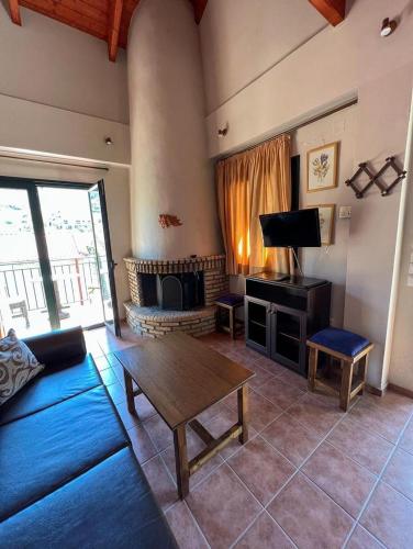 a living room with a couch and a table and a tv at All Seasons Πέτρινες Παραδοσιακές Κατοικίες in Kalavrita