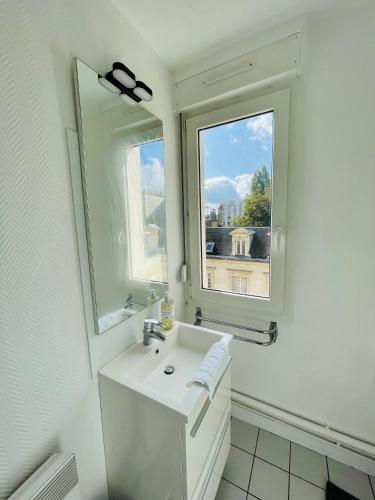 une salle de bain blanche avec un lavabo et une fenêtre dans l'établissement La terrasse de Clovis, à Reims