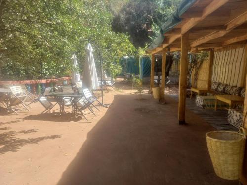 eine Terrasse mit einem Tisch, Stühlen und einem Sonnenschirm in der Unterkunft Maison d'hôte la source in Ouzoud
