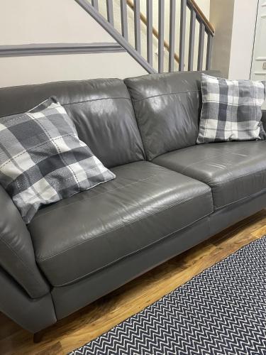 a black leather couch with two pillows on it at Charlesworth House in Crewe