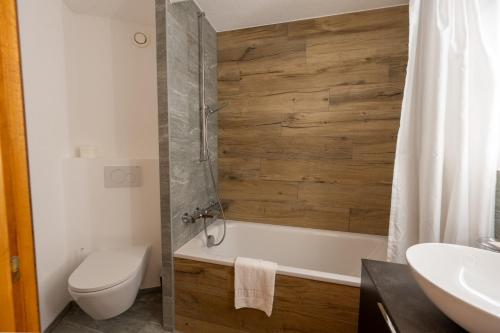 a bathroom with a tub and a toilet and a sink at Eden Resort Anzère in Anzère