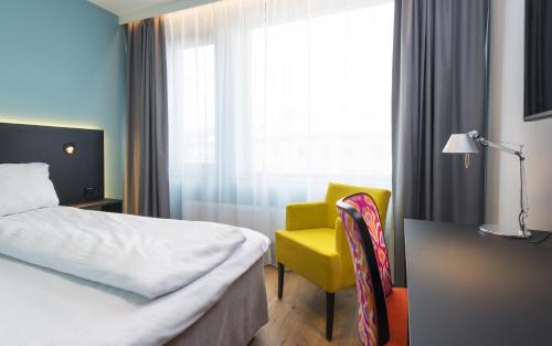 a hotel room with a bed and a yellow chair at Thon Hotel Vika Atrium in Oslo