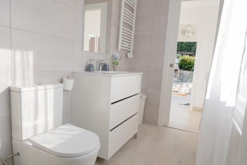 a white bathroom with a toilet and a sink at Casa Luna Rural Con Piscina y Jardín in Ourense