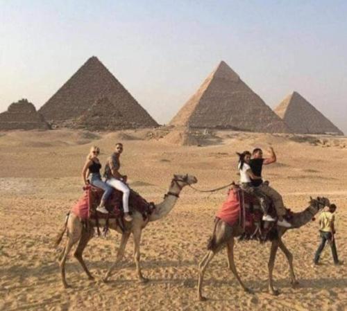a group of people riding on camels in the pyramids at Momen Pyramids Inn in Cairo