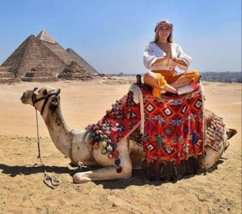 a woman sitting on a camel in front of the pyramids at Momen Pyramids Inn in Cairo