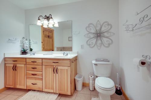 a bathroom with a toilet and a sink and a mirror at Lake Minocqua Condo with Shared Fire Pit! in Minocqua