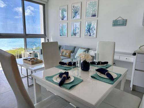 a kitchen and dining room with a white table and chairs at Azure 515 Aruba Vacation Sunset Breeze in Palm-Eagle Beach