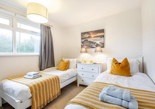 2 camas individuales en un dormitorio con ventana en Bryn Penmaen, en Pwllheli