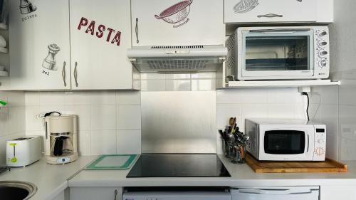 une cuisine avec des armoires blanches et un micro-ondes dans l'établissement Superbe appartement En baie de Somme, à Cayeux-sur-Mer