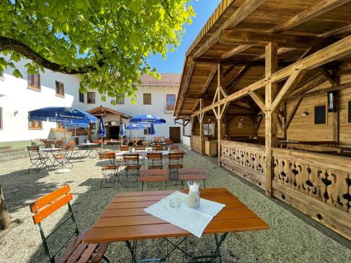 a wooden patio with tables and chairs and umbrellas at Landgasthaus zur Linde in Pleiskirchen