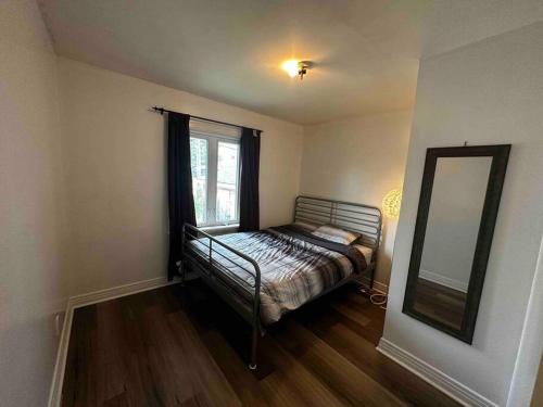 ein kleines Schlafzimmer mit einem Bett und einem Spiegel in der Unterkunft 3 Bedroom Near downtown Ottawa in Ottawa