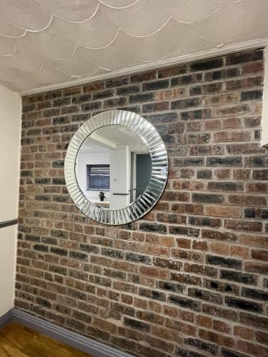 a brick wall with a circular mirror on it at Charlesworth House in Crewe