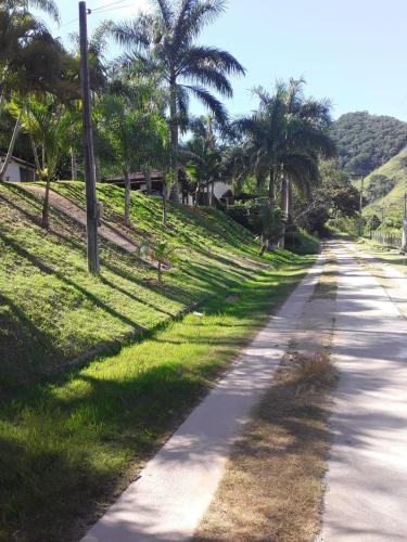 a road with palm trees on the side of a hill at Cantinho da Serra do Sana in Macaé