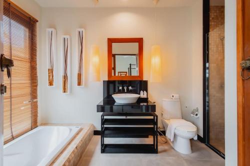 a bathroom with a tub and a sink and a toilet at Ivory Pool Villa in Nai Harn in Rawai Beach