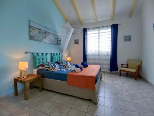 a bedroom with a bed and a chair and a window at Domaine de Fanélie in Deshaies