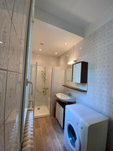 een badkamer met een wasmachine en een wastafel bij Pavillon indépendant avec jardin au calme, proche Paris in Houilles