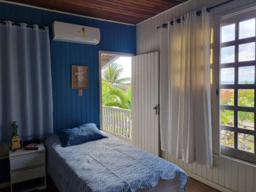 Schlafzimmer mit blauen Wänden und einem Bett mit Fenster in der Unterkunft Casa lindo aconchego praia mar in Itaparica Town