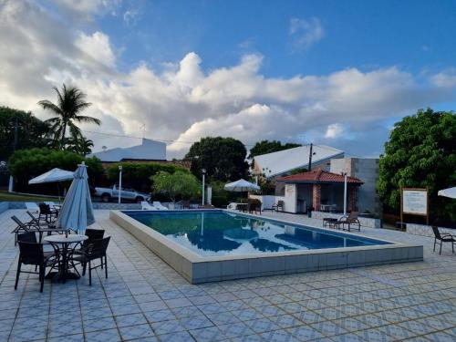 einen Pool mit Tischen und Stühlen sowie einen Tisch mit einem Sonnenschirm in der Unterkunft Casa lindo aconchego praia mar in Itaparica Town