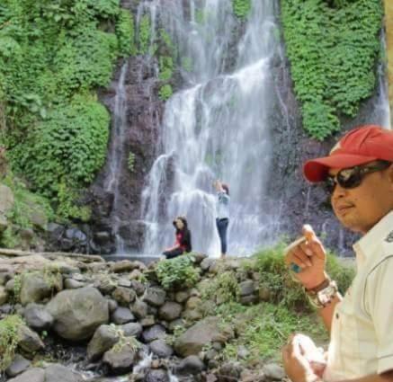 a man standing in front of a waterfall at Dannu's Homestay Ijen and Bromo Tour in Banyuwangi