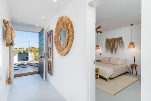 een witte slaapkamer met een bed en een spiegel bij Mermaid Cottage in Comporta