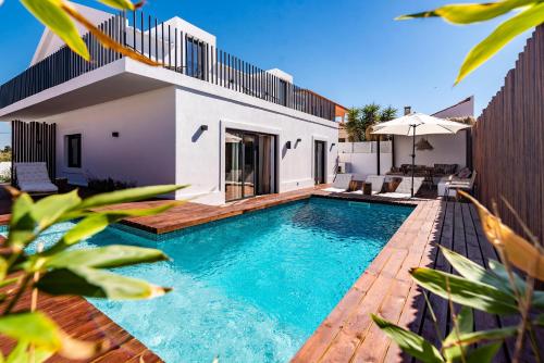 a swimming pool in the backyard of a house at Mermaid Cottage in Comporta