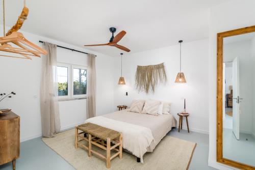 ein weißes Schlafzimmer mit einem Bett und einem Deckenventilator in der Unterkunft Mermaid Cottage in Comporta