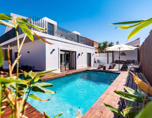 a swimming pool in the backyard of a house at Mermaid Cottage in Comporta
