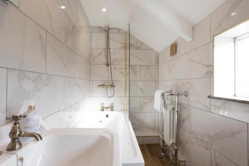a white bathroom with a sink and a shower at Bankside Cottage in Bedale