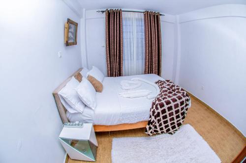 een slaapkamer met een bed met witte lakens en kussens bij Penthouse in Eldoret