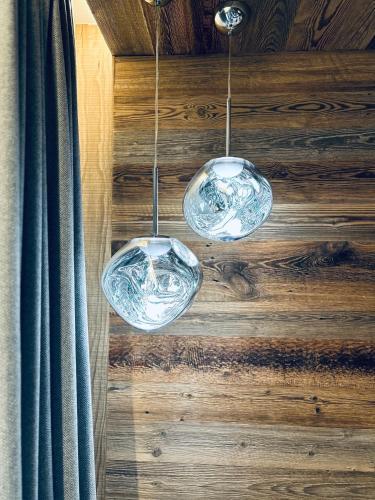 two glass wine glasses hanging from a wooden wall at Hameau des Prodains - Résidence in Morzine