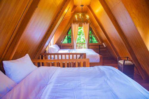 a attic bedroom with two beds and a window at Ban Kaew Mo Ra Glamping & Restaurant in Pang Mapha