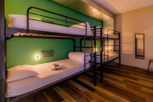 Ce lit se trouve dans un dortoir doté de 2 lits superposés et d'un mur vert. dans l'établissement Pintler's Portal Hostel, à Anaconda