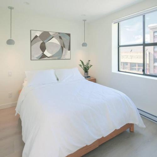 a white bedroom with a large bed and a window at Newly Renovated 1 Bedroom Condo in Japantown! Near Gastown & Railtown! in Vancouver