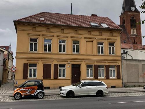a white car parked in front of a yellow building at FeWo Bismarck 29 in Stendal
