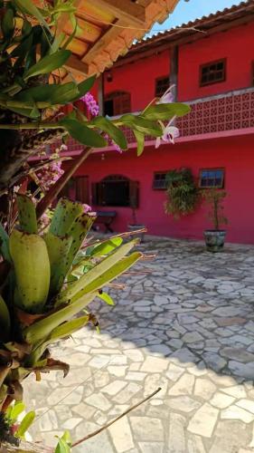 a red building with a stone courtyard with a plant at Pousada Blues in Ipiabas