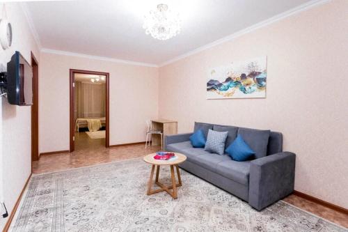 sala de estar con sofá azul y mesa en Яркая Квартира на Арбате en Almaty