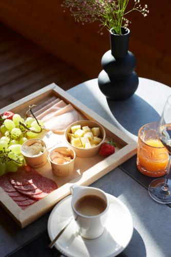a tray of food and a cup of coffee on a table at Alpenstolz Damüls Haus 3 - Stilvoll urlauben in den Bergen in Damuls